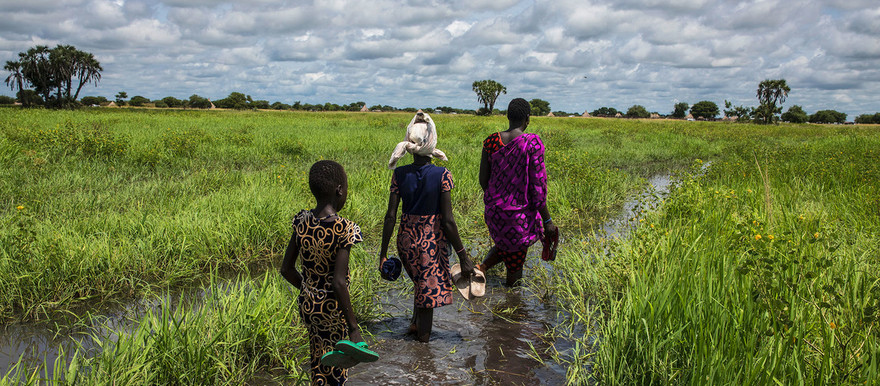 A woman and her family wade through a flooded plain to reach their home in Thaker, Unity state, South Sudan. [Photo:WFP/Gabriela Vivacqua]