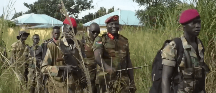 Major General Gabriel Moses Lokujo being escorted by his troops and holding a stick in Kajo-Keji County in September 2020. (Photo credit: Nyamilepedia)